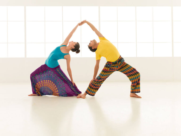 Twee personen doen yogaposes in een studio.