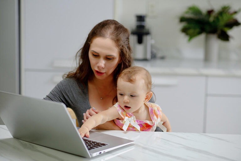 Woman and baby looking at laptop screen.